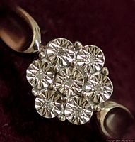 Close-up of the ring top showing the seven diamond accents arranged in a floral pattern with detailed starburst cuts on each stone, silver band visible.