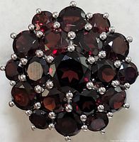 Front view of garnet cluster ring showing multiple round faceted garnet stones in silver setting.