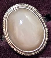 Close-up photo of the oval moonstone set in silver with rope edge detail, highlighting the translucent smooth surface and silver bezel setting.