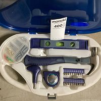 Open view of Catarina picture hanging tool set showing hammer, level, tape measure, screwdriver handle, bits, and hardware container.