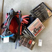 Overall lot contents including black and red Craftsman tool bag with tools spilling out showing combination wrenches, screwdriver bit set, multimeter, and packaging for tools