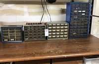 Four metal hardware organizer drawer units in sizes from small to tall, consisting of multiple clear plastic drawers. Drawers contain assorted hardware parts.