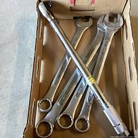 Large wrenches and torque wrench lying inside a cardboard box, showing all tools in one image.