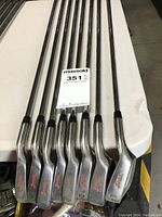 Eight Penn branded metal golf irons with black handles and red lettering on the club heads.