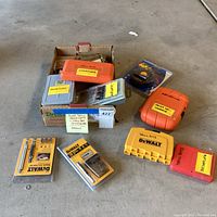 Box containing multiple power drill drive sets and cases, some labeled with yellow tape and handwritten notes.