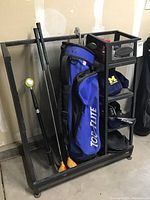 Full view of black Suncast golf organizer holding golf bag, clubs, and some accessories on bottom cubbies