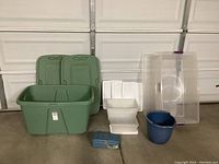 Wide view of all plastic storage containers including green bins, white containers, clear container, blue bucket, and small blue tin box