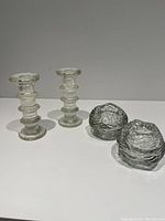 Pair of Pukeberg Sweden glass candle holders and two snowball textured glass tea light holders on a flat surface against a gray background.