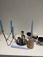 View of all candleholders and candles on a flat surface against a plain background, showing arrangement and color contrast.