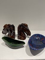 All four ceramic items including a pair of horse head bookends, a green planter, and a blue dish