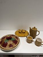 Full view of the set: cherry pie plate with lid, chicken devilled egg tray with salt and pepper shakers, ceramic teapot, cream and sugar bowl.