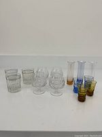 Full view of the collection showing all 12 glasses and vases together on a white surface.