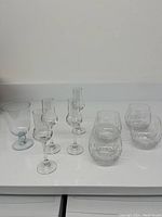 All 8 glasses visible including stemless cut wine glasses, liqueur glasses, and Kosta Boda Bernadette glass