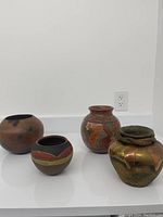 Photo showing four ceramic vases on a white surface against a white backdrop.