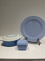 Photo shows the complete lot: a delphite blue serving plate on a stand, a small square Fridgie with lid, and the snowflake garland casserole dish with lid.