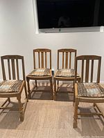 Front view of all four solid oak dining chairs with patterned cushions on wooden floor under television.