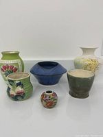 Overview of six various ceramics bases and pots including colorful floral and fruit hand-painted designs.