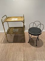 Image showing the full view of the black metal stool alongside the two-tier brass finish tea trolley.