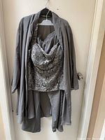 Front view of the 3-piece women's suit showing the dress pants, lacetop, and scarf wrap hanging together on a hanger.