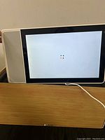 Lenovo Smart Display showing Google logo on screen indicating powering on, sitting on wooden surface with visible power cable.