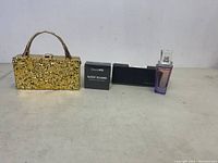Gold metal clutch purse with textured surface and gold handle next to Sleep MD Sleep Guard box and Kalina Remy perfume box.