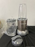 Four Nutribullet blender units shown with blender bases, blending cups, and lids, on a black surface including a plastic wrapped component.
