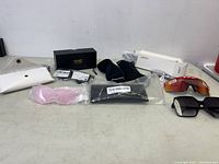 Overview photo of sunglasses lot showing multiple styles, pouches, and boxes on countertop.