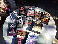 Photo of 11 audio book sets arranged on a table with visible titles by John Sandford, Stephen King, Michael Crichton, and others.