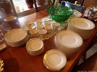 Overview of entire dish set including cups, saucers, plates, and green decorative bowl on a wooden table
