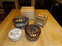 Five assorted decorative boxes arranged on wooden table including two painted wooden boxes, square wooden box, mosaic glass box and porcelain box