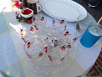 Top view of the cookie platters, six clear glass snowman mugs, blue glass, and various Christmas-themed ceramics on a white tablecloth.