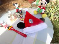 Photo of Mickey Mouse Santa hat, back scratcher, and small Mickey figurines on table outdoors