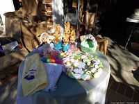 Photo showing all items on table: ceramic bunnies, green ceramic cracked basket, colorful plastic eggs, pastel Easter wreath, and two embroidered hand towels