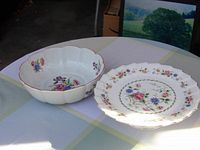 Photo of floral bowl and cake plate with scalloped edges and floral motif on a table