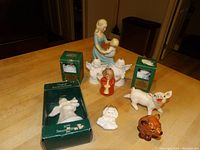 Photo of all figurines and boxed ornaments showing a mother and child figurine, angels, red angel, pig and dog figurines, and two boxed Hallmark ornaments
