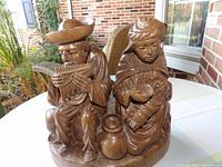 Front view showing man playing pan pipes and woman holding baby, with visible signature.