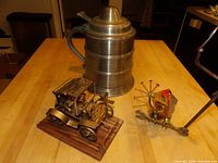 Full view showing the tractor and rooster metal figurines next to the beer stein cooler on a table.
