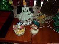 Overview photo showing three Beatrix Potter musical figurines and one bird-themed musical figurine on a wooden surface