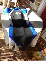 Top front view of the wet suit laid flat showing black and blue panels with front zipper and small size marking