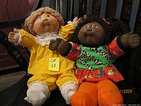 Photo of both dolls seated side by side showing full outfits and condition.