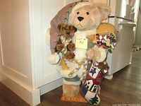 Front angle view of the large teddy bear with smaller bear and Christmas stocking, showing entire figure and base.