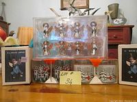 Front view of entire lot showing 2 unopened boxes of mache cherubs, metal angels in plastic packaging, and 4 metal glasses in original boxes