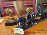 Double elephant lamp with brass-colored metal elephants on a black base and large metallic shade, showing overall good condition and some dents on the shade.