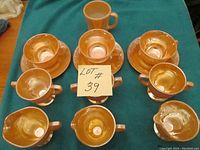 Top down view showing all items: 3 sugar bowls, 3 creamers, 3 cups and saucers, and 1 mug in Fire King Lustre finish.