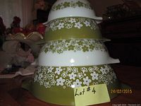 Four vintage Pyrex nesting bowls stacked showing floral pattern and handles