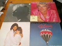 Eight vintage vinyl record albums displayed showing cover art for Rod Stewart Greatest Hits, Air Supply, Billy Joel's 52nd Street, Donna Summer, Barry White, Olivia Newton-John, Barbra Streisand and another artist.
