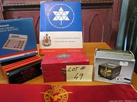Photo showing the Canada 1967 commemorative stamp box, Baoding balls in red box, a Yardley Black Label box, Royal Air Force pillow with insignia, and a slide viewer in original box on a wooden surface.