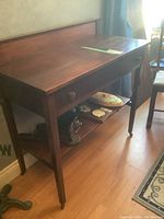 Sideboard full view showing shape, size, drawer and bottom shelf with small items on it