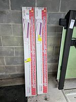 Two boxed electric baseboard heaters leaning against a cinder block wall.