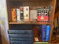 Shelf with VHS movies and books including The Story of Canada volumes and accounting books